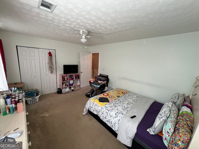 bedroom featuring a closet, a textured ceiling, ceiling fan, and carpet floors