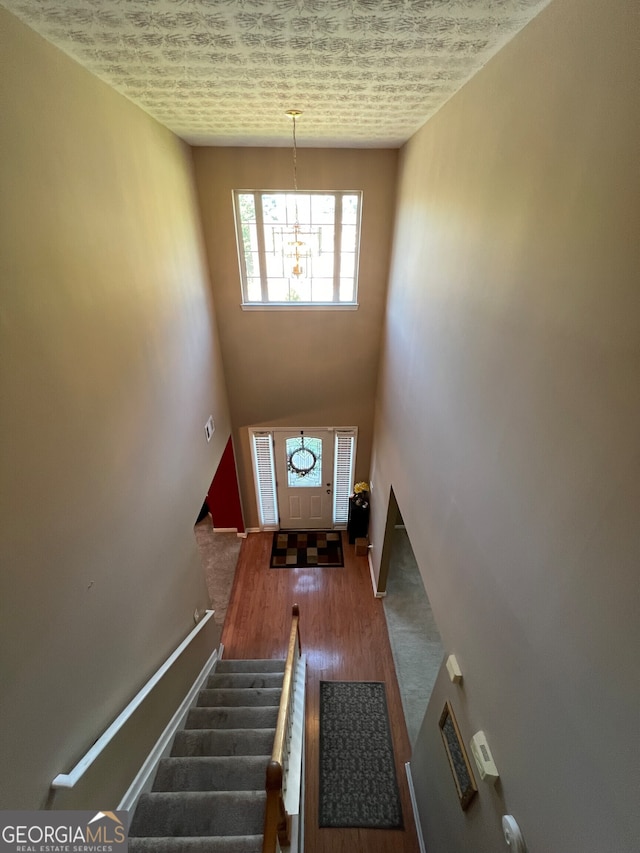 doorway to outside featuring wood-type flooring, a textured ceiling, and a chandelier