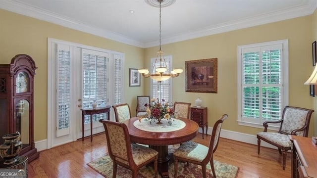 dining space with a chandelier, ornamental molding, a wealth of natural light, and light wood-type flooring