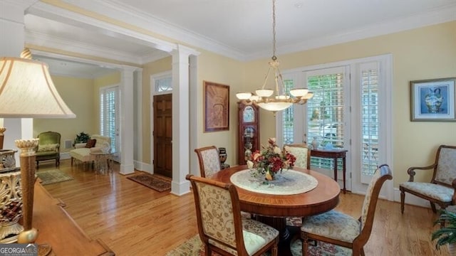 dining room with a notable chandelier, decorative columns, light hardwood / wood-style flooring, and ornamental molding