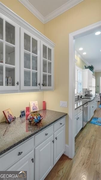 kitchen featuring ornamental molding, dishwasher, white cabinetry, and light wood-type flooring