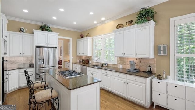 kitchen featuring stainless steel appliances, tasteful backsplash, a kitchen island, and white cabinets