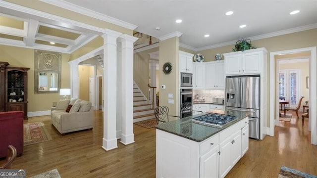 kitchen with appliances with stainless steel finishes, a kitchen island, hardwood / wood-style floors, white cabinetry, and crown molding