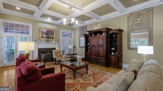 living room with a notable chandelier, light hardwood / wood-style floors, coffered ceiling, and beamed ceiling