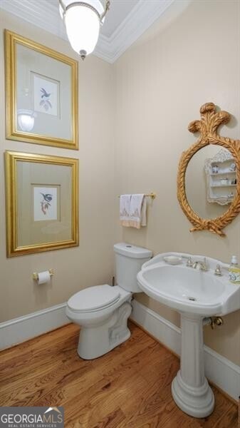 bathroom with toilet, ornamental molding, and wood-type flooring