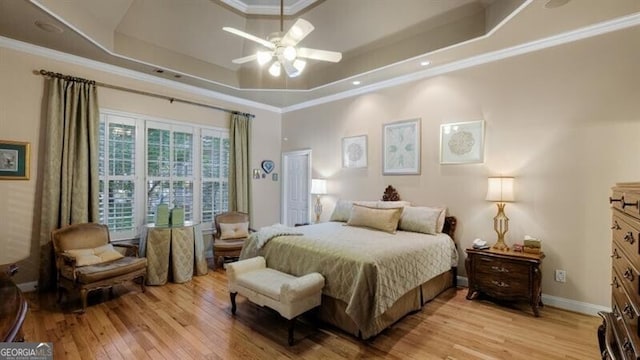 bedroom featuring ornamental molding, a tray ceiling, light hardwood / wood-style floors, and ceiling fan