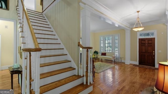 entryway with hardwood / wood-style floors, crown molding, and decorative columns