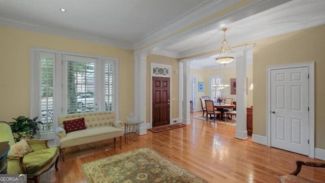 foyer entrance with decorative columns, ornamental molding, and hardwood / wood-style floors