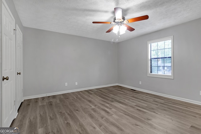 spare room featuring ceiling fan, hardwood / wood-style flooring, and a textured ceiling