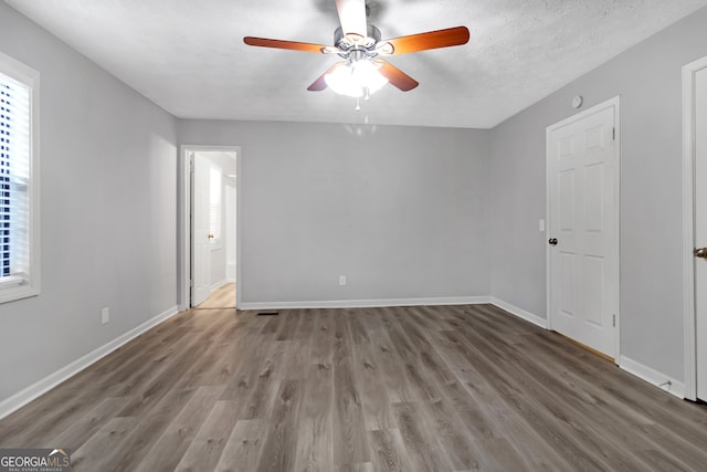 empty room featuring ceiling fan, a textured ceiling, and dark hardwood / wood-style flooring