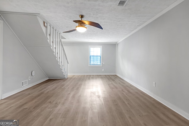 unfurnished living room with ornamental molding, hardwood / wood-style flooring, a textured ceiling, and ceiling fan