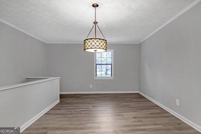 spare room with crown molding, wood-type flooring, and a textured ceiling