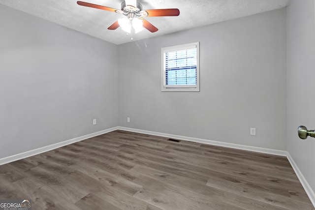 spare room with ceiling fan, a textured ceiling, and dark hardwood / wood-style flooring