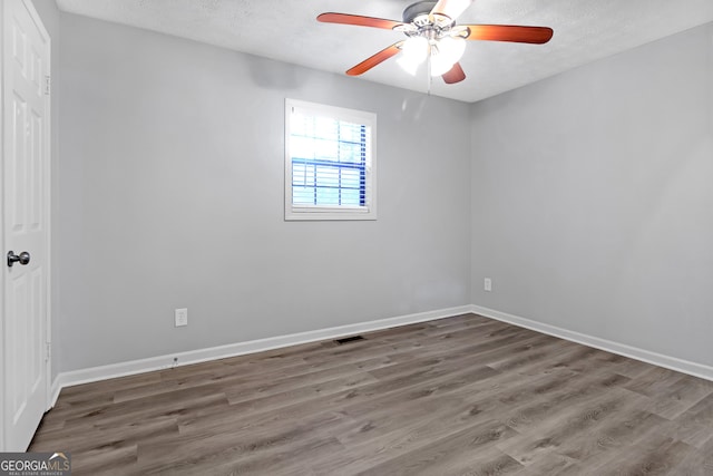 empty room with a textured ceiling, hardwood / wood-style flooring, and ceiling fan