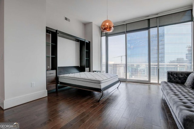 bedroom featuring expansive windows and dark hardwood / wood-style flooring