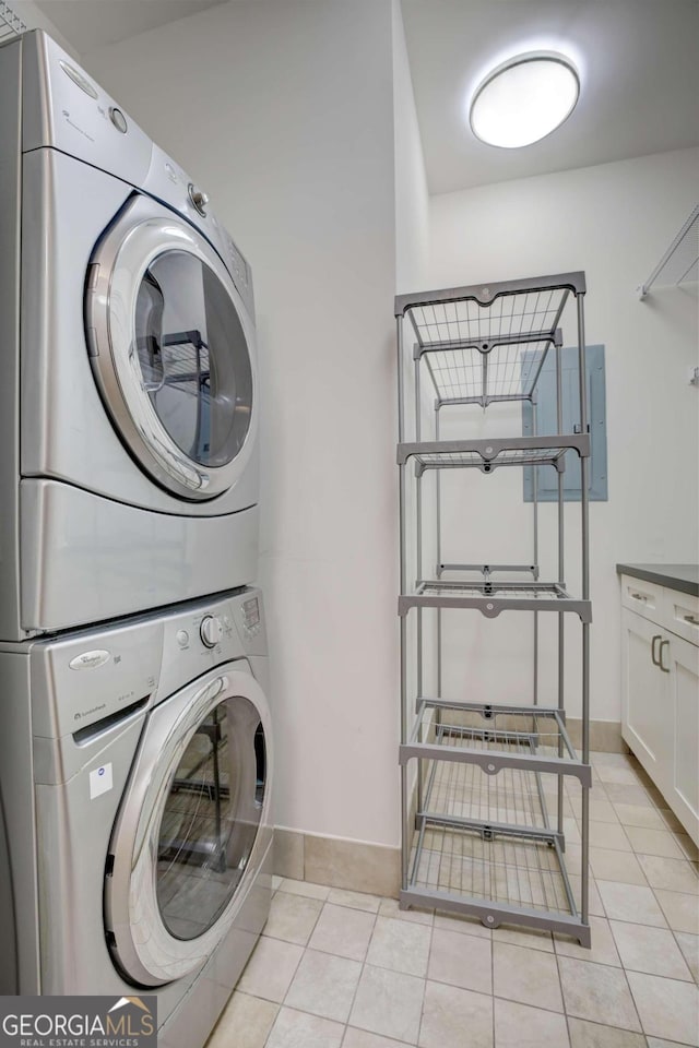 laundry area with light tile patterned floors and stacked washer and dryer