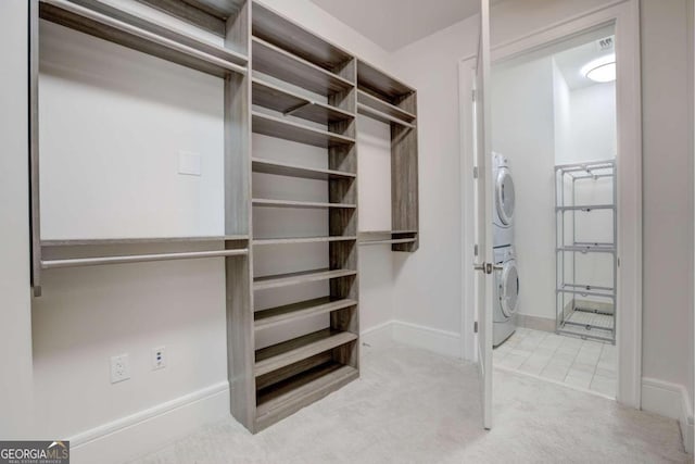 walk in closet featuring light colored carpet and stacked washer and dryer