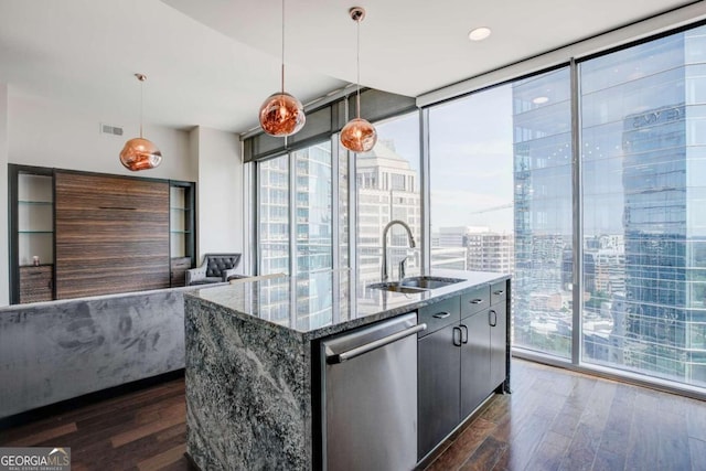 kitchen with a kitchen island with sink, stainless steel dishwasher, dark wood-type flooring, pendant lighting, and sink