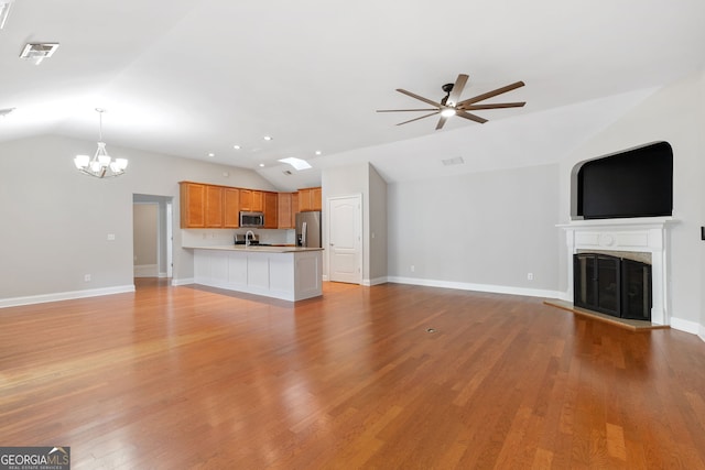 unfurnished living room with light wood-type flooring, ceiling fan with notable chandelier, and lofted ceiling