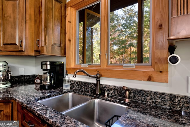 kitchen with dark stone counters, a wealth of natural light, and sink