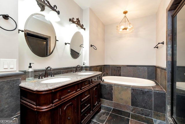 bathroom featuring a notable chandelier, vanity, and a relaxing tiled tub