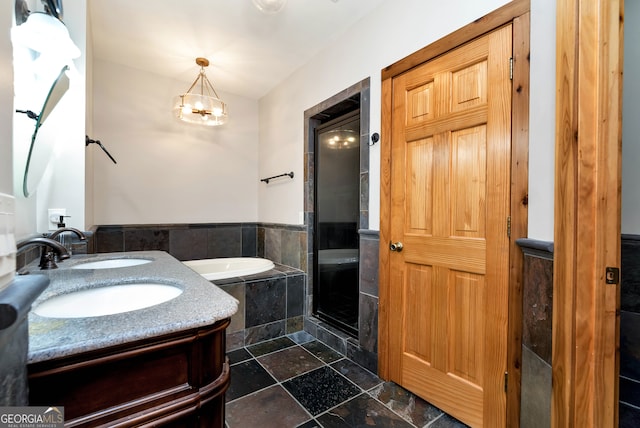 bathroom with vanity, tiled tub, and an inviting chandelier