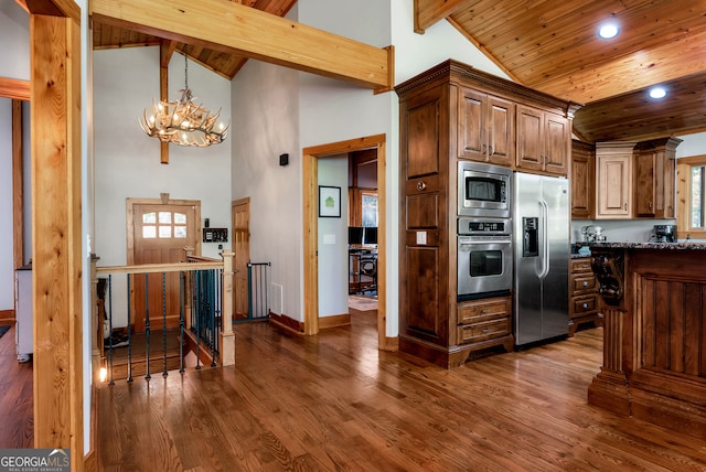 kitchen featuring stainless steel appliances, dark wood-type flooring, beamed ceiling, and an inviting chandelier