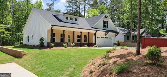 modern farmhouse style home with a front yard, a porch, and a garage