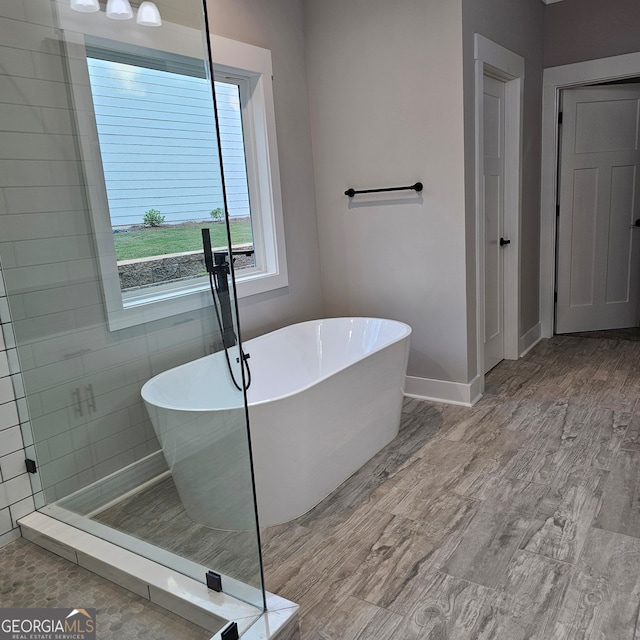 bathroom with a tub to relax in, tile walls, and hardwood / wood-style floors