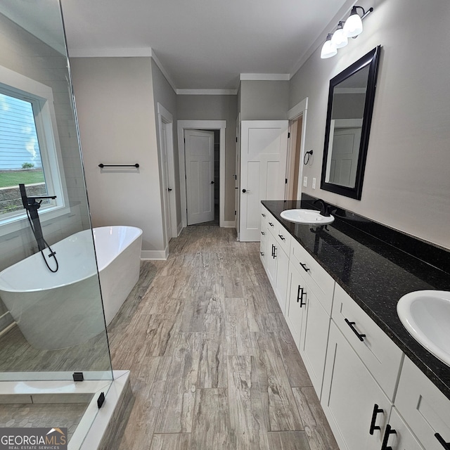 bathroom with vanity, a tub to relax in, hardwood / wood-style floors, and ornamental molding