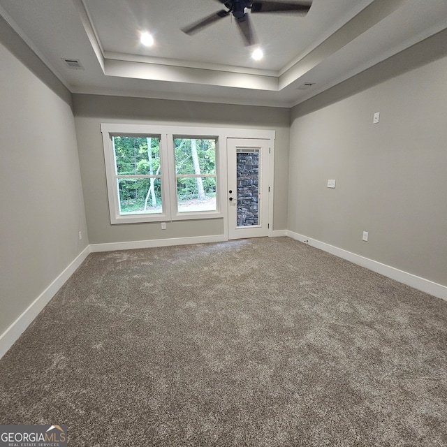 unfurnished room with ornamental molding, carpet flooring, a tray ceiling, and ceiling fan