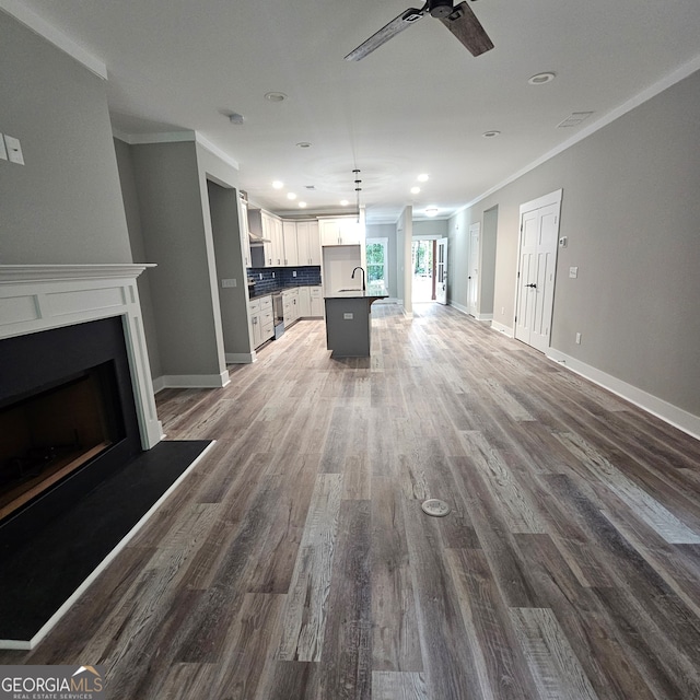 unfurnished living room featuring ornamental molding, hardwood / wood-style floors, sink, and ceiling fan