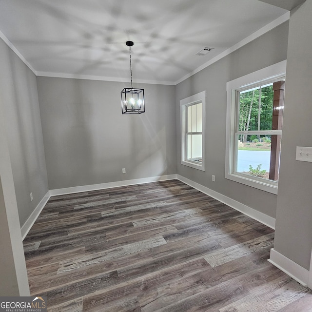 unfurnished dining area with an inviting chandelier, crown molding, and dark wood-type flooring