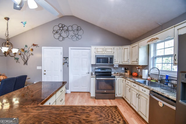 kitchen with light hardwood / wood-style floors, sink, appliances with stainless steel finishes, decorative light fixtures, and vaulted ceiling