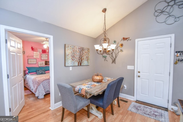 dining area featuring vaulted ceiling, hardwood / wood-style flooring, and ceiling fan with notable chandelier