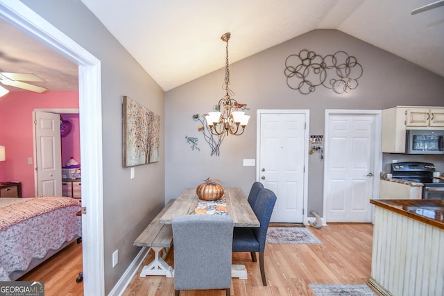 dining room featuring light hardwood / wood-style floors, ceiling fan with notable chandelier, and vaulted ceiling