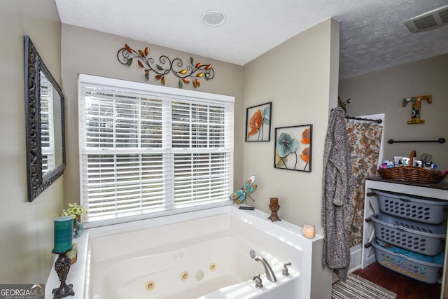 bathroom featuring independent shower and bath, a textured ceiling, and a healthy amount of sunlight