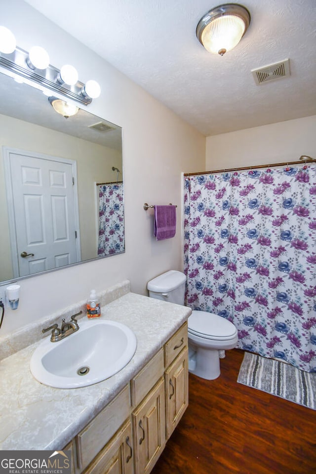 bathroom with a shower with curtain, vanity, a textured ceiling, hardwood / wood-style flooring, and toilet