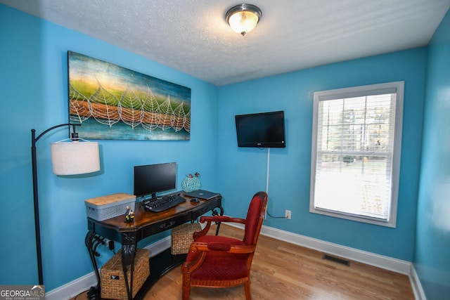 home office with hardwood / wood-style flooring and a textured ceiling