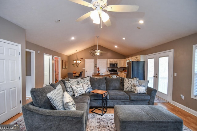 living room with light wood-type flooring, vaulted ceiling, french doors, and ceiling fan with notable chandelier