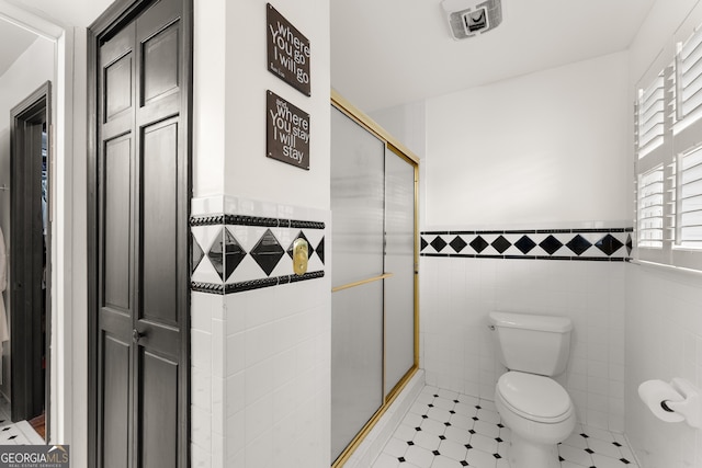 bathroom with toilet, tile walls, tile patterned floors, and walk in shower