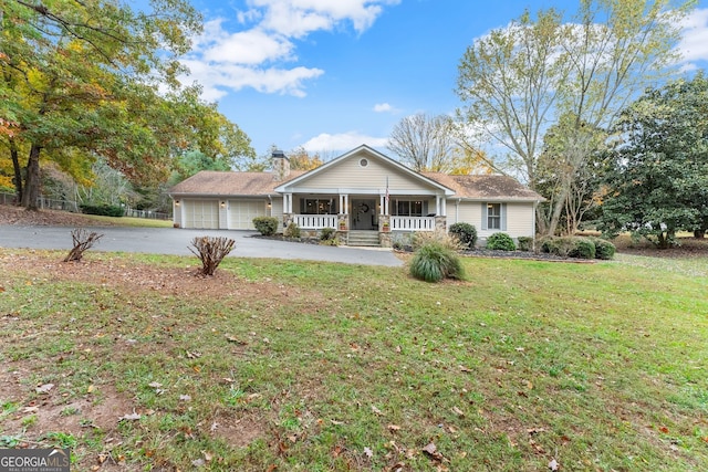 ranch-style home featuring a garage, covered porch, and a front yard