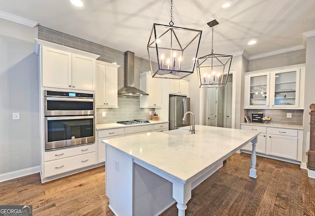 kitchen with stainless steel appliances, white cabinets, hardwood / wood-style floors, wall chimney exhaust hood, and decorative light fixtures