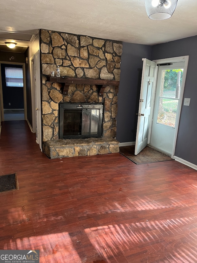 unfurnished living room with a stone fireplace, hardwood / wood-style floors, and a textured ceiling