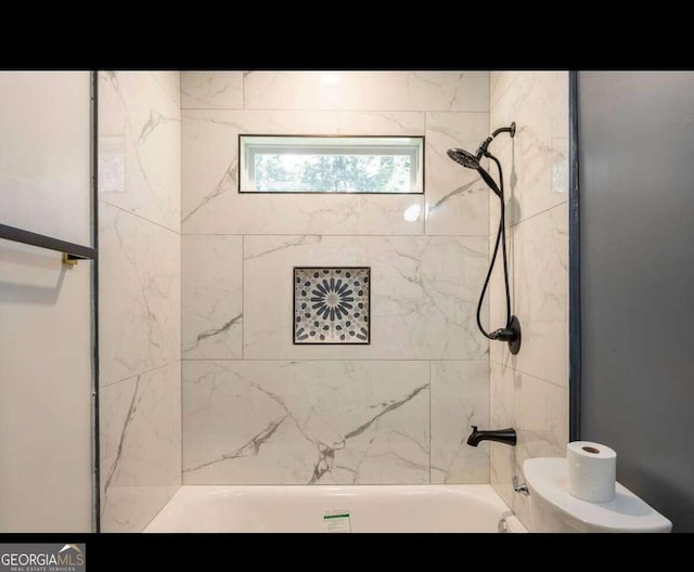 bathroom with tiled shower / bath combo and toilet