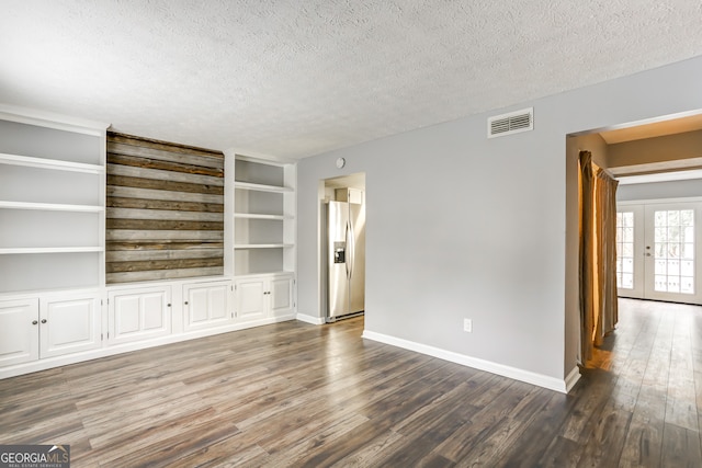 unfurnished living room with a textured ceiling, french doors, built in features, and dark hardwood / wood-style floors