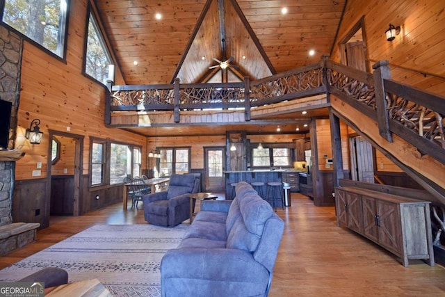 living room featuring a towering ceiling, hardwood / wood-style flooring, ceiling fan, and wood ceiling