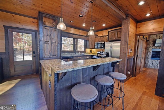 kitchen with a center island, stainless steel appliances, light stone counters, and light hardwood / wood-style floors