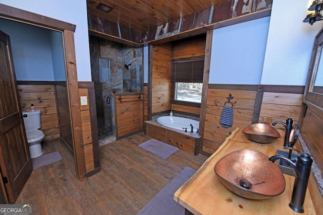 full bathroom with wood walls, hardwood / wood-style floors, wooden ceiling, and sink