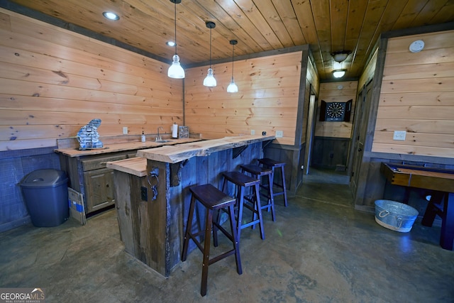 bar featuring pendant lighting, wood walls, butcher block counters, and wooden ceiling